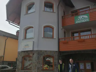 two men standing in front of a building at Riverside Pines Luce Apartments with Balcony - One Bedroom Apartment with Balcony in Luče