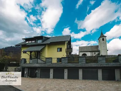 a yellow building with a clock tower on top of it at Bled Prestigious and Stylish Apartments - Classic One Bedroom Apartment with Balcony in Bled