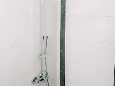 a shower in a white tiled bathroom at Bled Prestigious and Stylish Apartments - Classic One Bedroom Apartment with Balcony in Bled