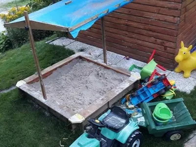 a sandbox with toys in the grass next to a house at Comfortable Zre e Apartment - One Bedroom Apartment in Zreče