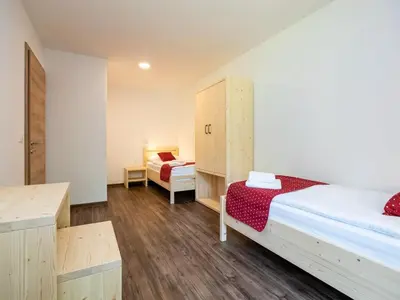 a small room with two beds and a cabinet at The Woodland Nook Apartments Bohinj - Classic Two Bedroom Apartment with Balcony in Bohinj