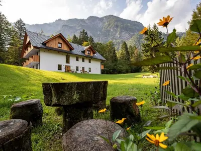 a house on a hill with a fence and flowers at The Woodland Nook Apartments Bohinj - Classic Two Bedroom Apartment with Balcony in Bohinj
