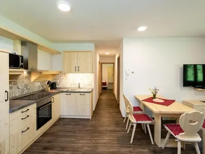 a kitchen with white cabinets and a table and chairs at The Woodland Nook Apartments Bohinj - Classic Two Bedroom Apartment with Balcony in Bohinj