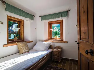 a small bedroom with a bed and two windows at Rustic Authentic Holiday Home with Terrace and Wood Stove - Three Bedroom Holiday Home with Terrace in Ljubno