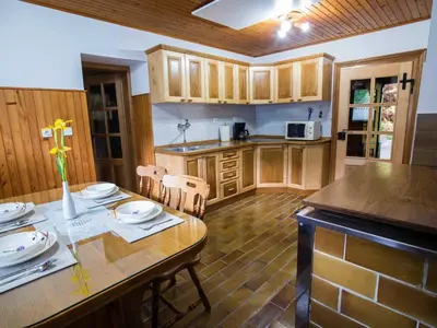 a kitchen with wooden cabinets and a table and chairs at Rustic Authentic Holiday Home with Terrace and Wood Stove - Three Bedroom Holiday Home with Terrace in Ljubno