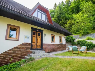 a house with two chairs in the yard at Rustic Authentic Holiday Home with Terrace and Wood Stove - Three Bedroom Holiday Home with Terrace in Ljubno
