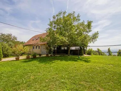 a house with a tree in a yard at Rustic Charm Cottage Country House with Sauna - Five Bedroom Holiday Home with Sauna in Bizeljsko