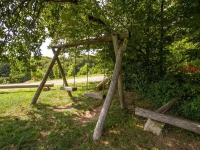 a swing set sitting in a field under a tree at Rustic Charm Cottage Country House with Sauna - Five Bedroom Holiday Home with Sauna in Bizeljsko