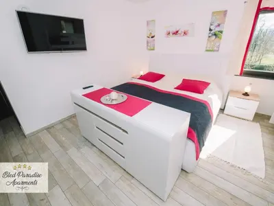 a white bedroom with a bed and a flat screen tv at Bled Prestigious and Stylish Apartments - Standard Studio Apartment with Terrace in Bled
