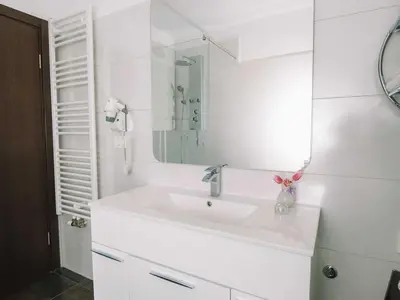 a white bathroom with a sink and a mirror at Bled Prestigious and Stylish Apartments - Standard Studio Apartment with Terrace in Bled