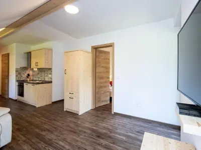 a living room with wooden flooring and a kitchen at The Woodland Nook Apartments Bohinj - Comfort Two Bedroom Apartment with Balcony in Bohinj