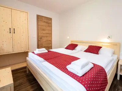 a bedroom with two beds with red and white sheets at The Woodland Nook Apartments Bohinj - Comfort Two Bedroom Apartment with Balcony in Bohinj