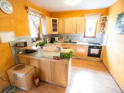 a kitchen with wooden cabinets and a clock on the wall at One Bedroom Holiday Home with Terrace and Garden in Krška Vas