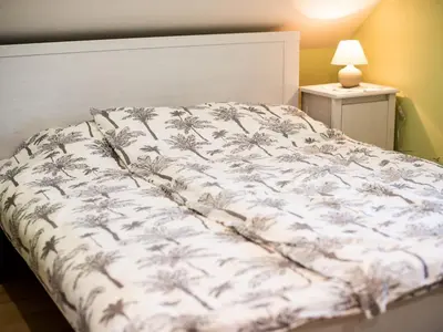 a bed with a white bedspread with palm trees on it at One Bedroom Holiday Home with Terrace and Garden in Krška Vas