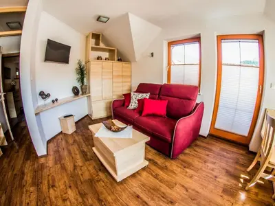 a living room with a red couch and a table at Riverside Pines Luce Apartments with Balcony - Studio Apartment with Balcony in Luče