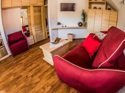 a living room with a red couch and a chair at Riverside Pines Luce Apartments with Balcony - Studio Apartment with Balcony in Luče