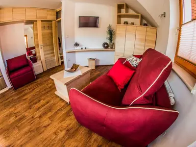 a living room with a red chair and a couch at Riverside Pines Luce Apartments with Balcony - Studio Apartment with Balcony in Luče