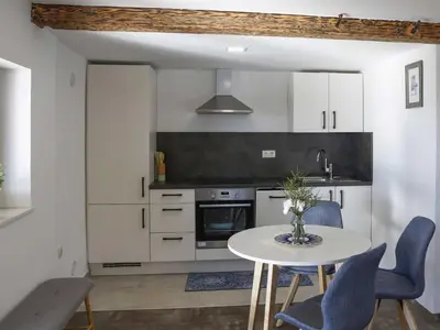 a kitchen with white cabinets and a table and chairs at Mountain Vibrant and Timeless Apartment with Sauna - Studio Apartment with Terrace in Dravograd