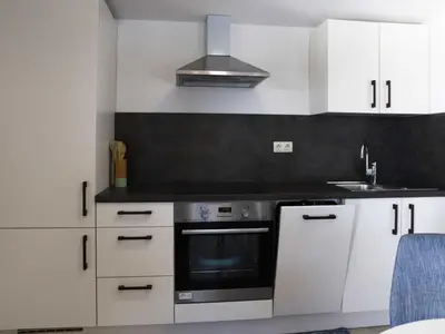 a kitchen with white cabinets and a stove top oven at Mountain Vibrant and Timeless Apartment with Sauna - Studio Apartment with Terrace in Dravograd