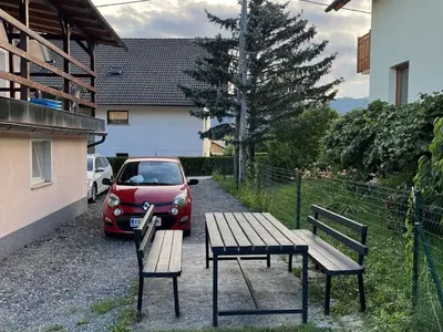 a red car parked next to a table and two benches at Meadow Tranquil Apartments with Evergreen Garden - One Bedroom Apartment in Žirovnica