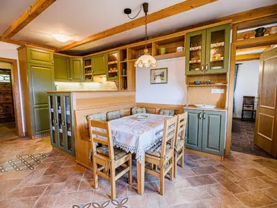 a kitchen with green cabinets and a table with chairs at Hidden Authentic Haven Apartments - Two Bedroom Apartment with Balcony in Sevnica