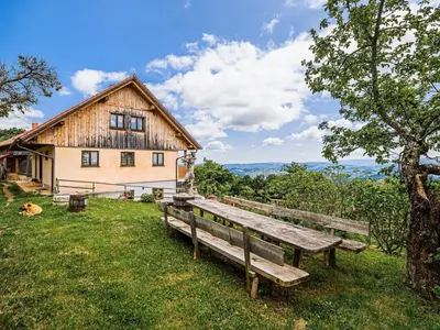 a wooden bench sitting in the grass in front of a house at Hidden Authentic Haven Apartments - Two Bedroom Apartment with Balcony in Sevnica
