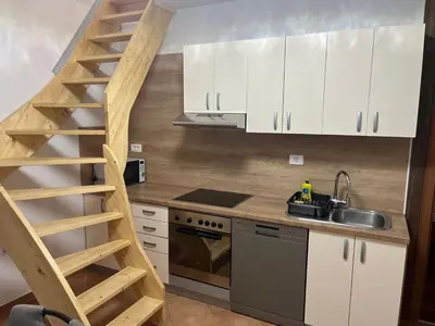 a kitchen with white cabinets and a wooden staircase at Meadow Tranquil Apartments with Evergreen Garden - Two Bedroom Apartment in Žirovnica