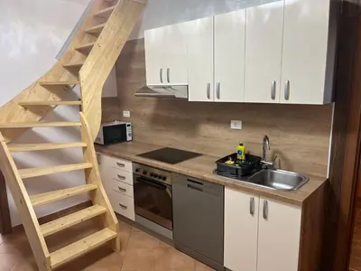 a kitchen with white cabinets and a sink and a ladder at Meadow Tranquil Apartments with Evergreen Garden - Two Bedroom Apartment in Žirovnica