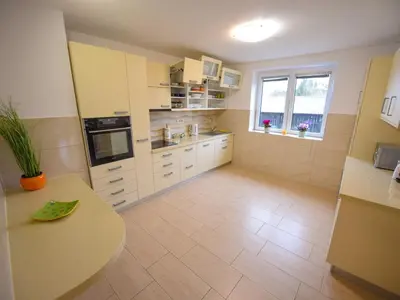 a kitchen with white cabinets and a table in it at Cozy Luxe Holiday Home with Natural Thermal Bath - Seven Bedroom Holiday Home in Cerklje ob Krki