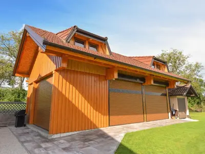 a house with two garage doors in a yard at Cozy Luxe Holiday Home with Natural Thermal Bath - Seven Bedroom Holiday Home in Cerklje ob Krki
