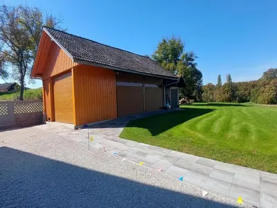 a building with a grassy yard next to a house at Cozy Luxe Holiday Home with Natural Thermal Bath - Seven Bedroom Holiday Home in Cerklje ob Krki