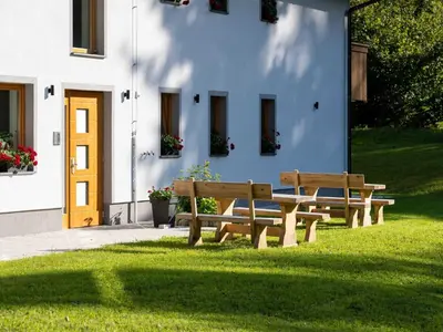 two benches sitting in the grass in front of a building at The Woodland Nook Apartments Bohinj - Two Bedroom Apartment with Balcony in Bohinj