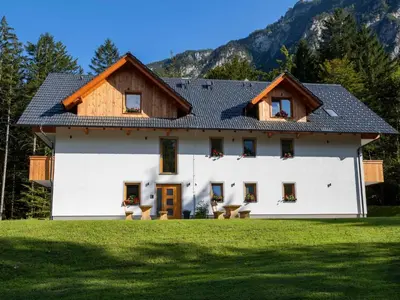 a white house with a wooden roof at The Woodland Nook Apartments Bohinj - Two Bedroom Apartment with Balcony in Bohinj