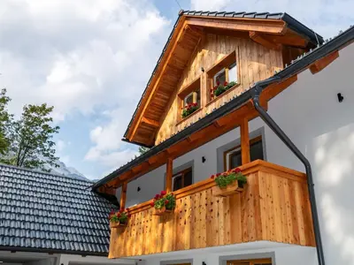 a wooden house with two windows and potted plants at The Woodland Nook Apartments Bohinj - Two Bedroom Apartment with Balcony in Bohinj