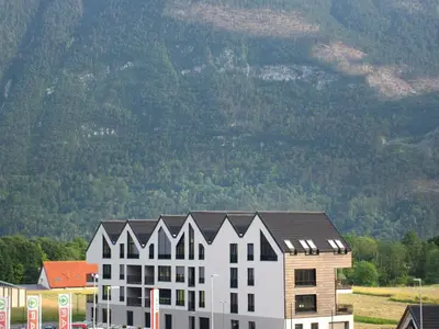 a large white building with a mountain in the background at Bovec Chic Apartment with Sauna - One Bedroom Apartment with Balcony in Bovec
