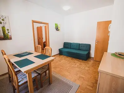 a living room with a table and a blue couch at Bovec Picturesque Mountain Vista Residences - One Bedroom Apartment in Bovec