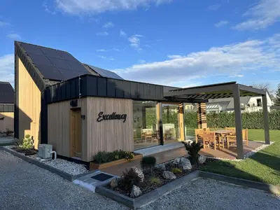 a building with a black roof and a patio at Elegant Warm Bliss Hideaway Escape Lodge - Holiday Home with Hot-Tub and Sauna in Šenčur