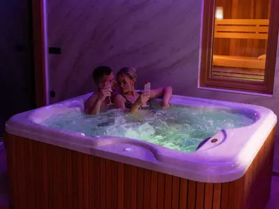 a man and a woman sitting in a bath tub at Elegant Warm Bliss Hideaway Escape Lodge - Holiday Home with Hot-Tub and Sauna in Šenčur