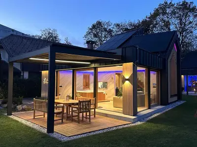 a house with a table and chairs on a deck at Elegant Warm Bliss Hideaway Escape Lodge - Holiday Home with Hot-Tub and Sauna in Šenčur