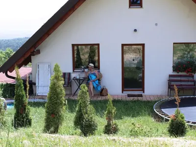 a woman sitting on the porch of a house at Rustic Refuge Glamping with Hot-Tub and Sauna - Two Bedroom Apartment with Terrace in Zreče