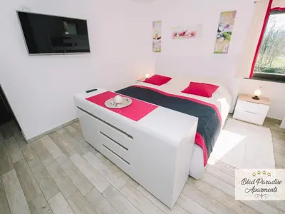 a white bedroom with a bed and a flat screen tv at Bled Prestigious and Stylish Apartments - Standard One Bedroom Apartment with Balcony in Bled