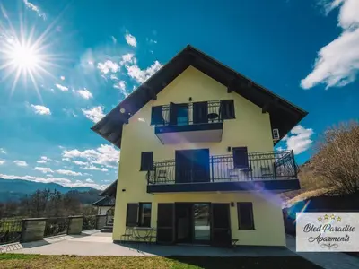 a house with a balcony and the sun in the sky at Bled Prestigious and Stylish Apartments - Standard One Bedroom Apartment with Balcony in Bled