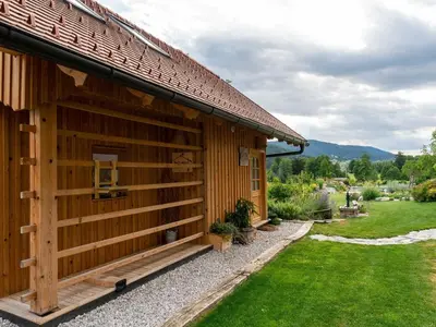 a log cabin with a green lawn next to it at Echo Valley Hillside Holiday Home with Sauna - Two Bedroom Holiday Home with Sauna in Ribnica