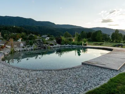 a pool of water with a wooden boardwalk in a yard at Echo Valley Hillside Holiday Home with Sauna - Two Bedroom Holiday Home with Sauna in Ribnica