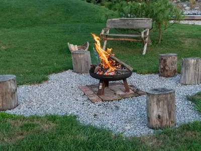a fire pit in a yard with logs and a bench at Echo Valley Hillside Holiday Home with Sauna - Two Bedroom Holiday Home with Sauna in Ribnica