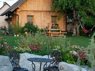 a garden with two tables and chairs in front of a building at Echo Valley Hillside Holiday Home with Sauna - Two Bedroom Holiday Home with Sauna in Ribnica