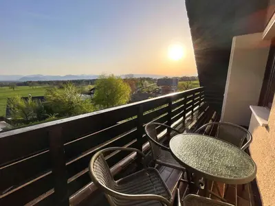 a balcony with a table and chairs and the sunset at Two Bedroom Apartment with Balcony and Mountain View in Preddvor