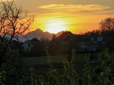 a sunset with the mountains in the background at Two Bedroom Apartment with Balcony and Mountain View in Preddvor
