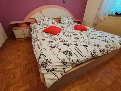 a bed with a black and white comforter and red pillows at Brezovica Spacious Family-Friendy Apartment - Two Bedroom Apartment with Balcony in Smarjeske Toplice