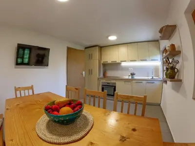 a kitchen with a wooden table with a bowl of fruit at Hillside Haven Holiday Home with Sauna and Hot-Tub - One Bedroom Holiday Home with Sauna and Hot-Tub in Podbočje
